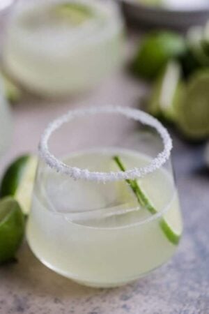 A close up of a Margarita with lime wedge and a salt rim.