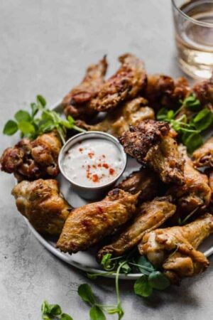 Grilled smoked chicken wings on a plate with blue cheese dressing for dipping.