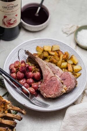 Roast rack of lamb with roasted grapes and potatoes.