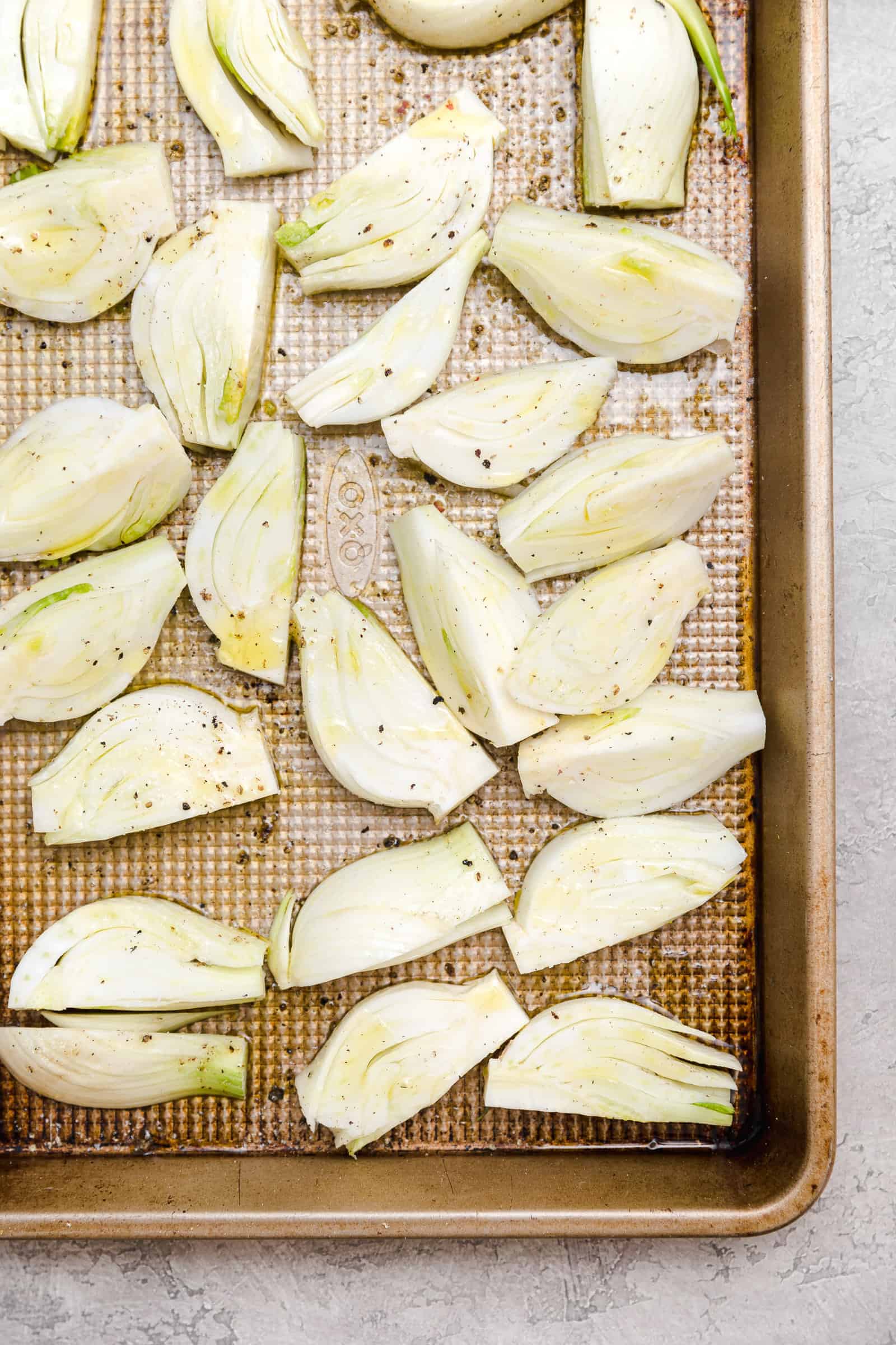 slices of fennel bulb on a baking sheet with olive oil, salt, and pepper