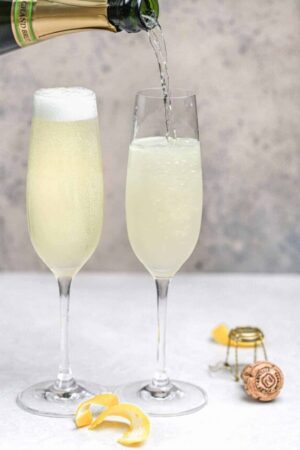 Champagne being poured into flute with gin, lemon juice, and simple syrup.