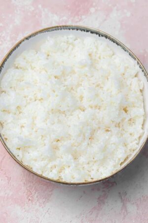 Sushi rice in a white bowl with seasoning.