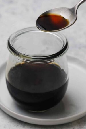 Teriyaki sauce in a jar with a spoon.