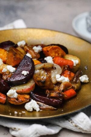 Roasted root vegetables with goat cheese on a gold plate.