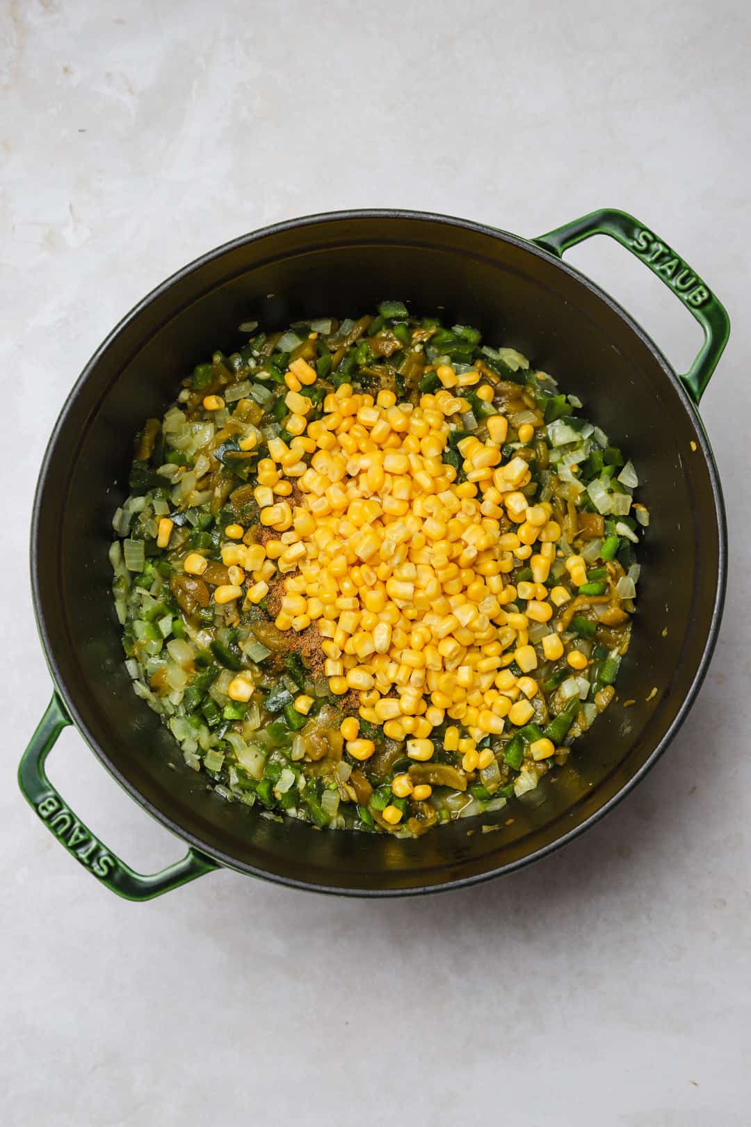 Fresh corn added to a soup pot with sautéed vegetables.