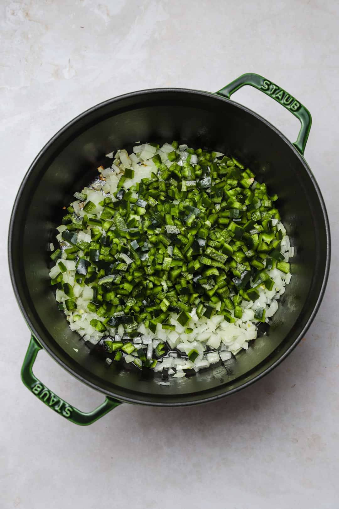 Onions and peppers sautéing in a soup pot.