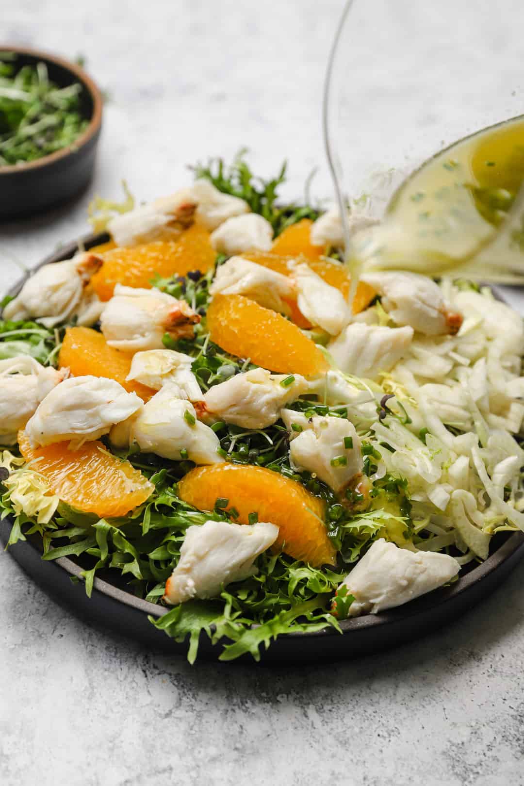 Orange citrus dressing being poured on crab salad