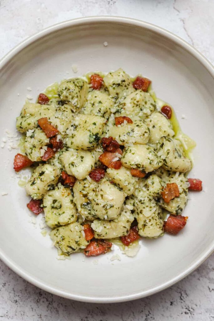 Pesto gnocchi with pancetta and mascarpone in a bowl.