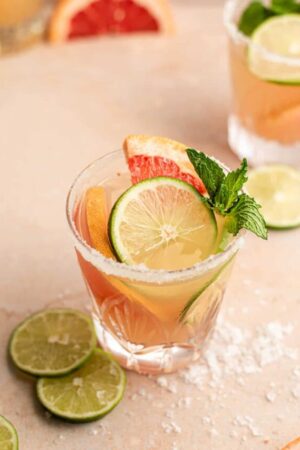 Grapefruit margarita with lime wedges and fresh mint.