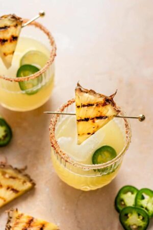 Grilled pineapple margarita in glasses with tajin along the rim.