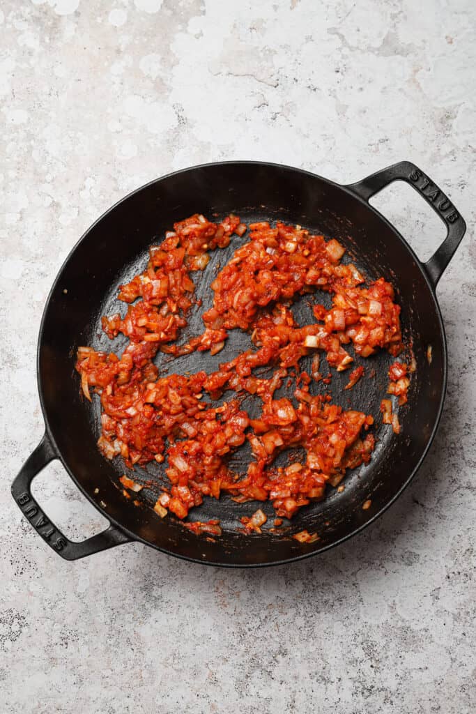 Tomato paste cooking in skillet until deep red and caramelized.
