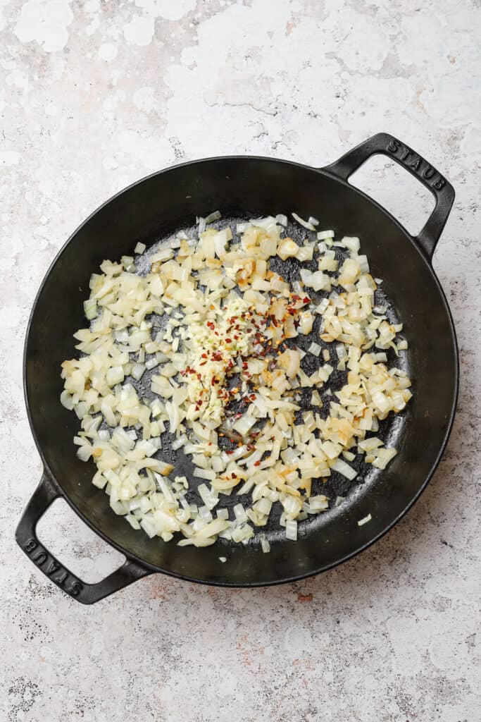 Sautéed onion, garlic, and red pepper flakes in a pan.