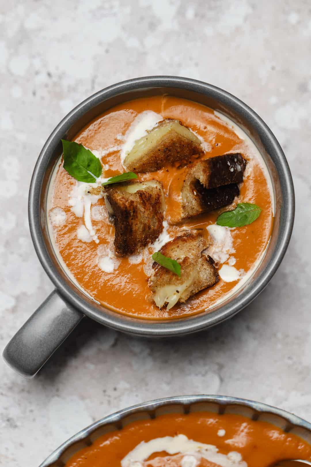 Mug of tomato soup with grilled cheese dipped inside.