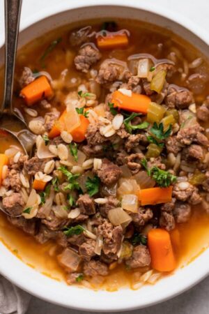 Beef & barley soup with carrots and parsley in a bowl.