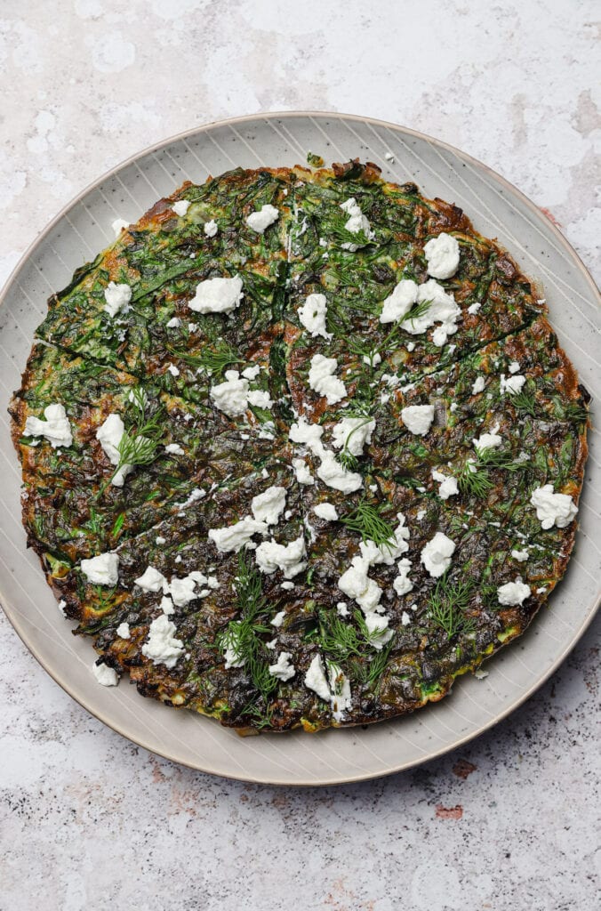 Spinach frittata with goat cheese on a gray plate.