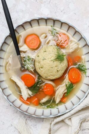 Chicken and matzo ball soup with carrots and fresh dill.