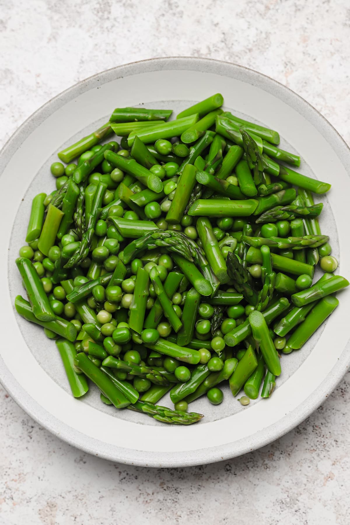 Blanched asparagus and English peas in a bowl.