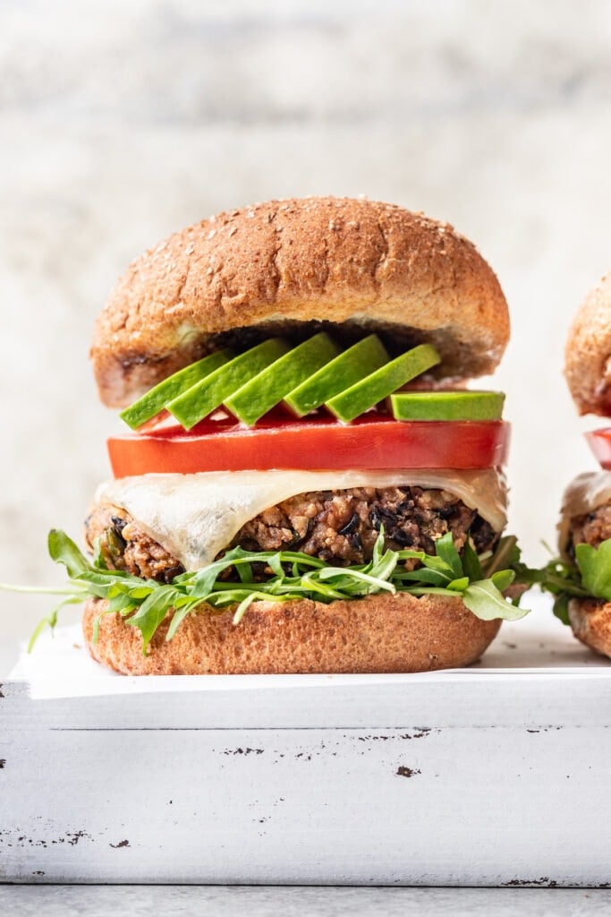 Kenji's black bean burgers with avocado tomato and melted cheese on buns.