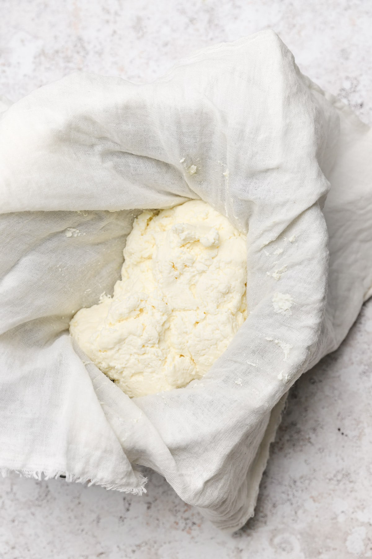 Straining ricotta cheese over cheesecloth.