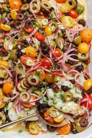Baked Mediterranean cod with tomatoes olives garlic and red onion.