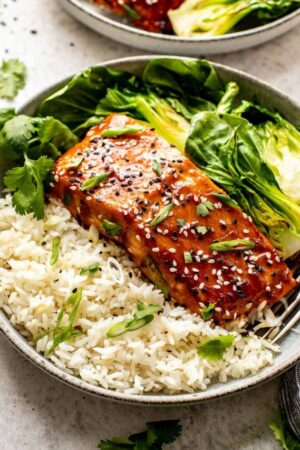 Miso salmon fillets with sesame seeds and scallions in a rice bowl.