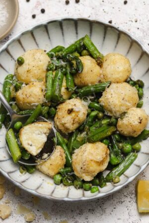 Soft pillowy ricotta gnudi with fresh English peas and asparagus.