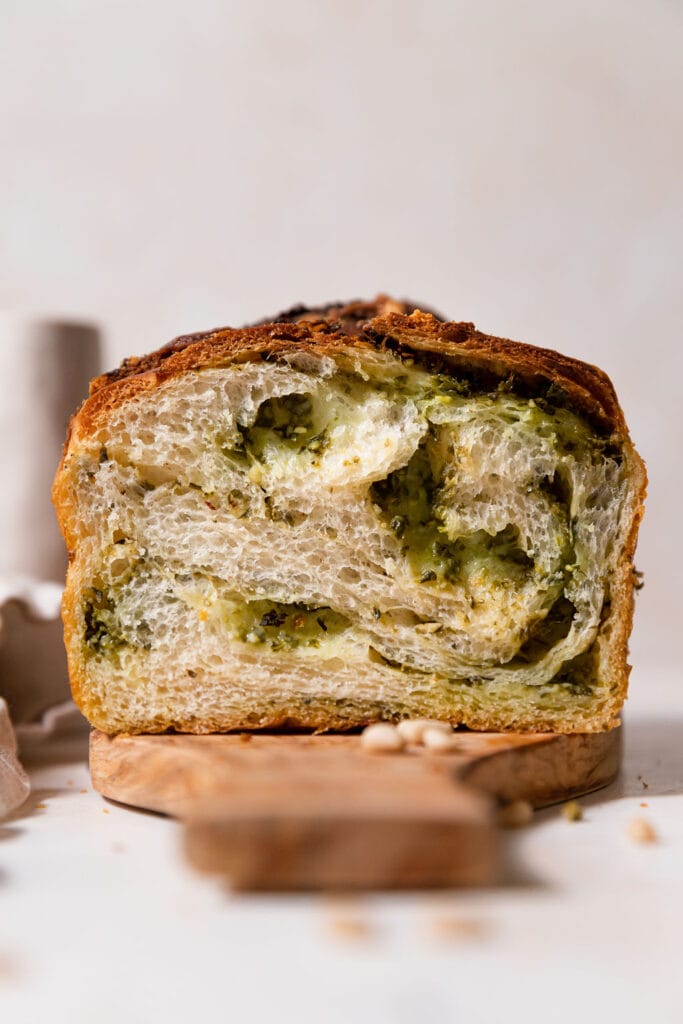 Cheesy braided pesto dough on a cutting board.