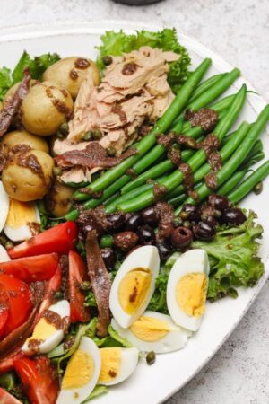 French nicoise salad with tunat capers olives tomatoes potatoes and hard boiled eggs.