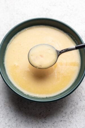 Orange citrus beurre blanc with a spoon in a bowl.