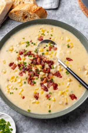 Close up of creamy corn chowder with bacon bits in bowl.