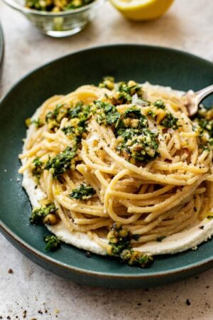 Creamy lemon ricotta pasta on a pkate with gremolata on top.