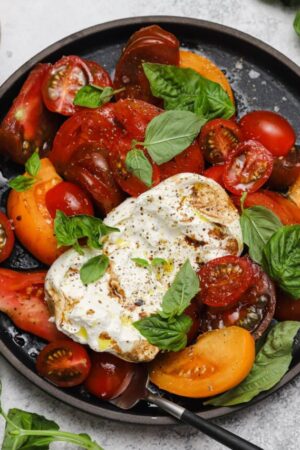Light summer tomato salad with burrata cheese truffle oil and fresh basil.