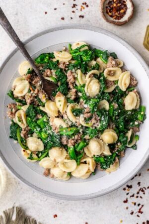 Orecchiette with sausage and broccoli rabe in bowl with spoon.