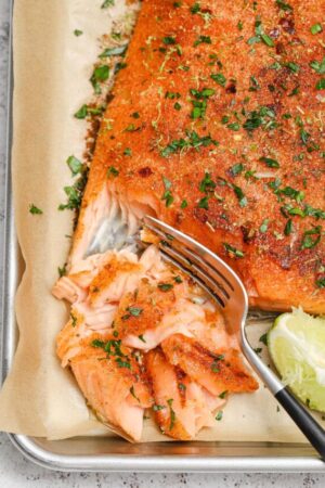 Slow baked cajun salmon with blackening spice and lime wedges.