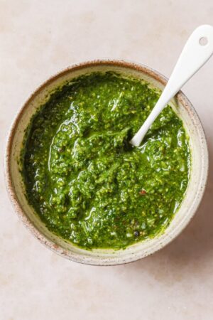 Pistachio pesto in a bowl with a spoon.