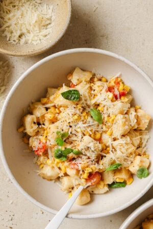 Tender ricotta gnocchi in a bowl with corn and tomatoes.