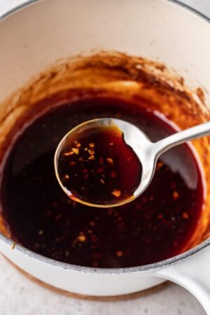 Teriyaki sauce in spoon over pot.