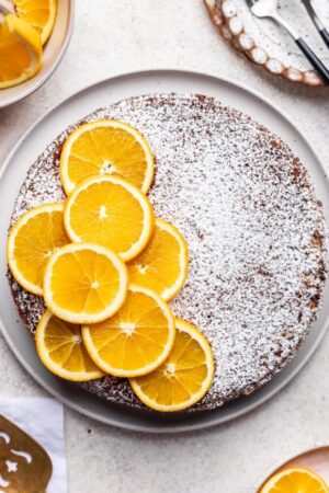Baked orange ricotta cake decorated with fresh orange slices and confectioners sugar.