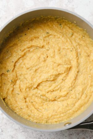 Creamy polenta with Parmigiano Reggiano cheese in a sauce pan.