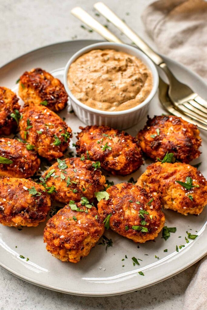 Fresh salmon croquettes made with mashed potatoes on a plate with dipping sauce.