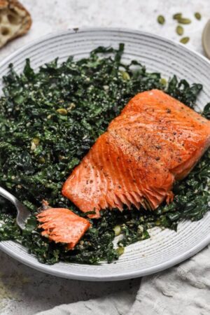 Kale salad with tender and flaky pan seared salmon on top.