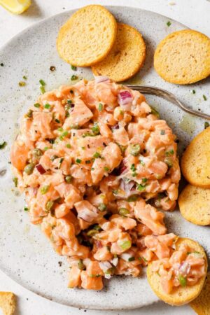 Scooping raw salmon onto a cracker.