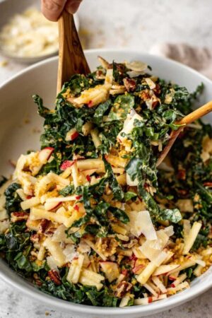 Tossing a kale salad with lemon salad dressing.