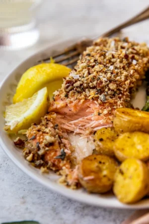 Pecan crusted salmon cut into with a fork on a plate.