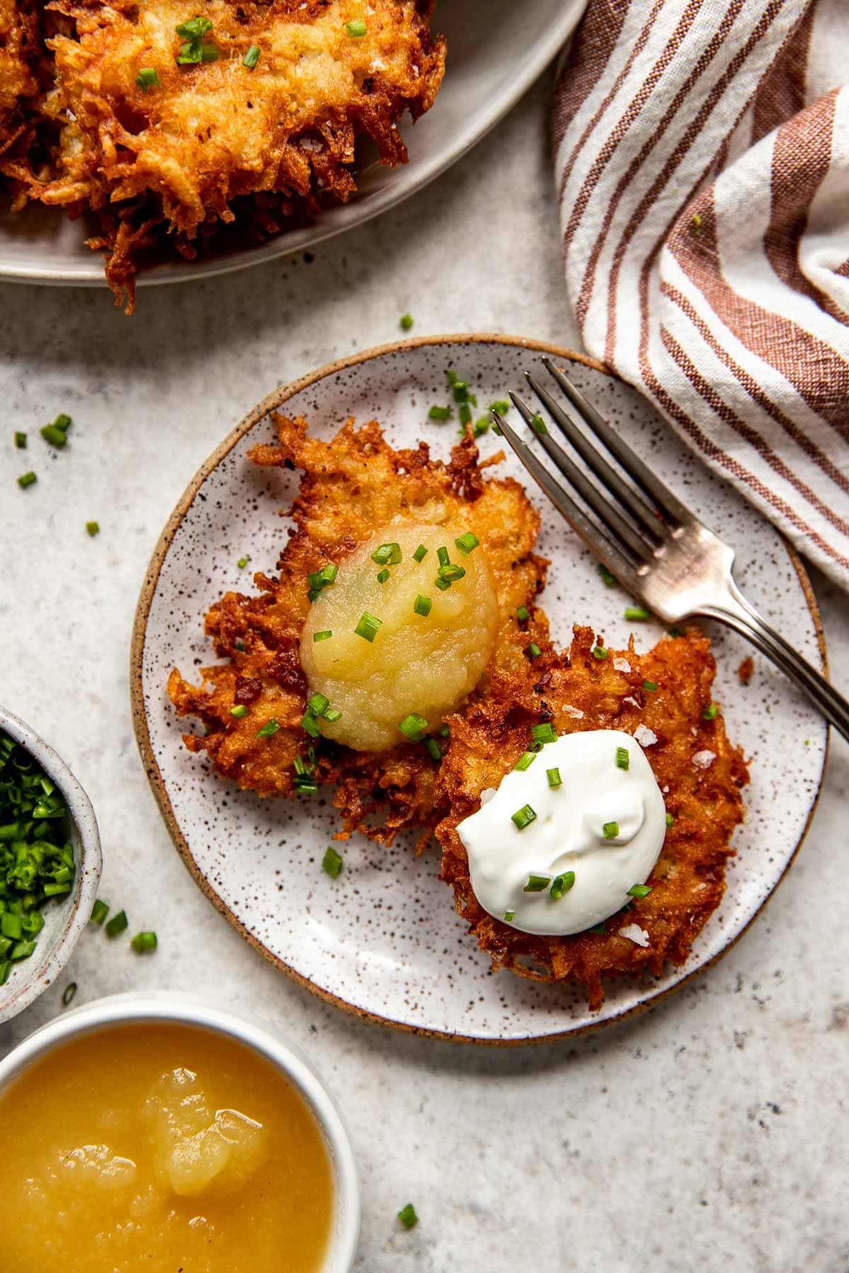 Potato pancakes with sour cream and applesauce on a plate.