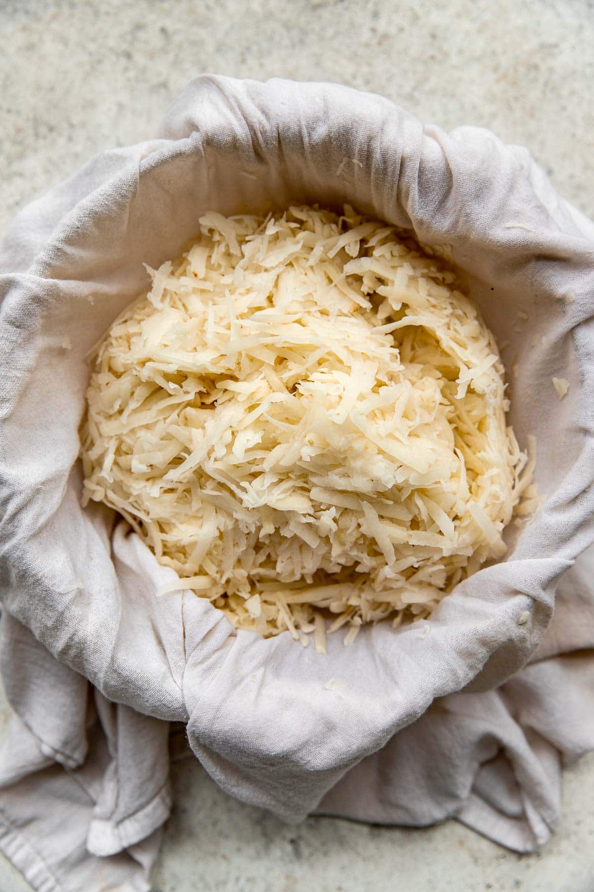 Straining grated potatoes in cheesecloth.