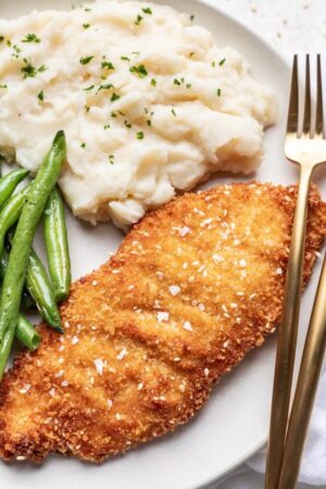 Coating chicken cutlets in whisked eggs.
