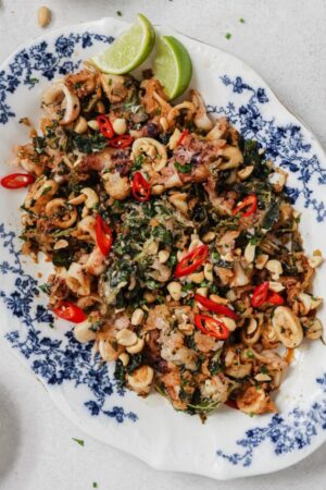 Fried calamari and watercress salad on a plate with chiles and peanuts.