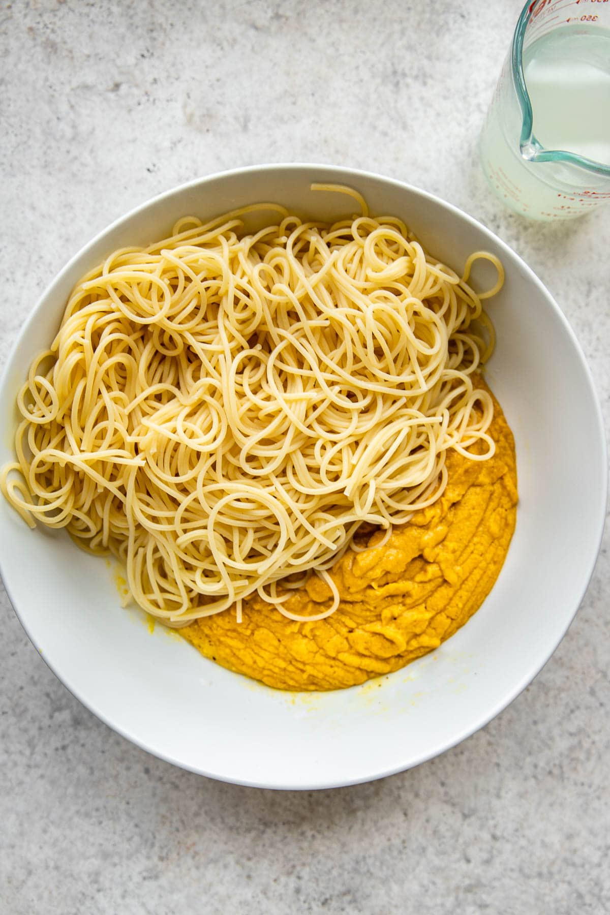 Adding cooked pasta to a large bowl.
