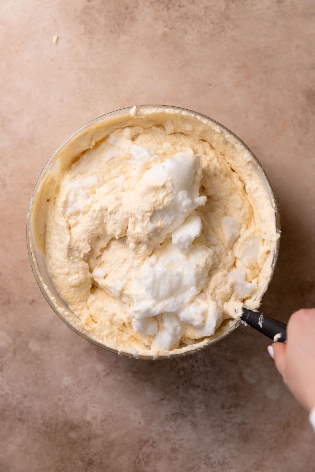 Adding egg whites into zabaglione in a mixing bowl.